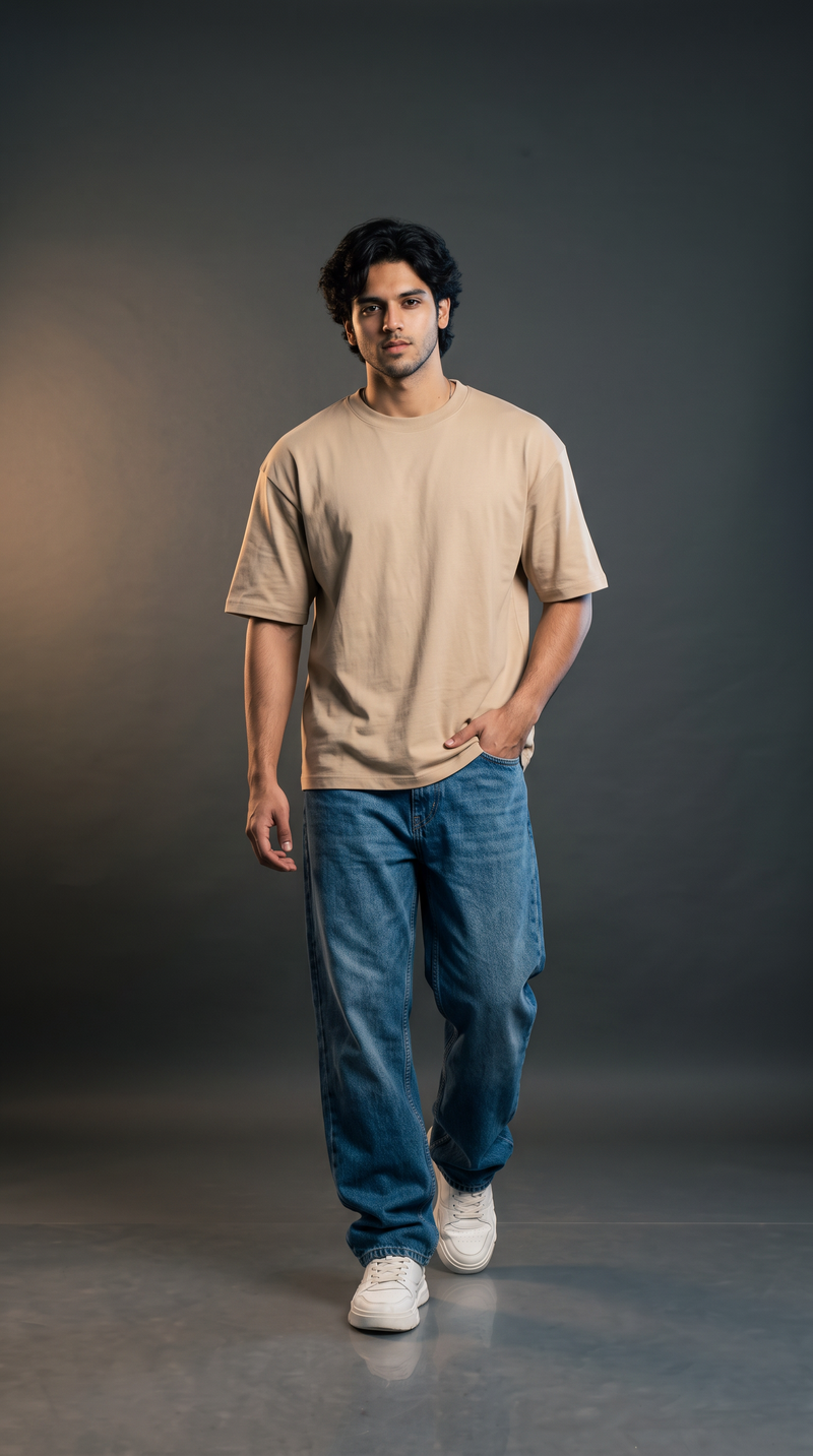 Man wearing sand beige oversized t-shirt in 240 GSM cotton terry with blue baggy jeans